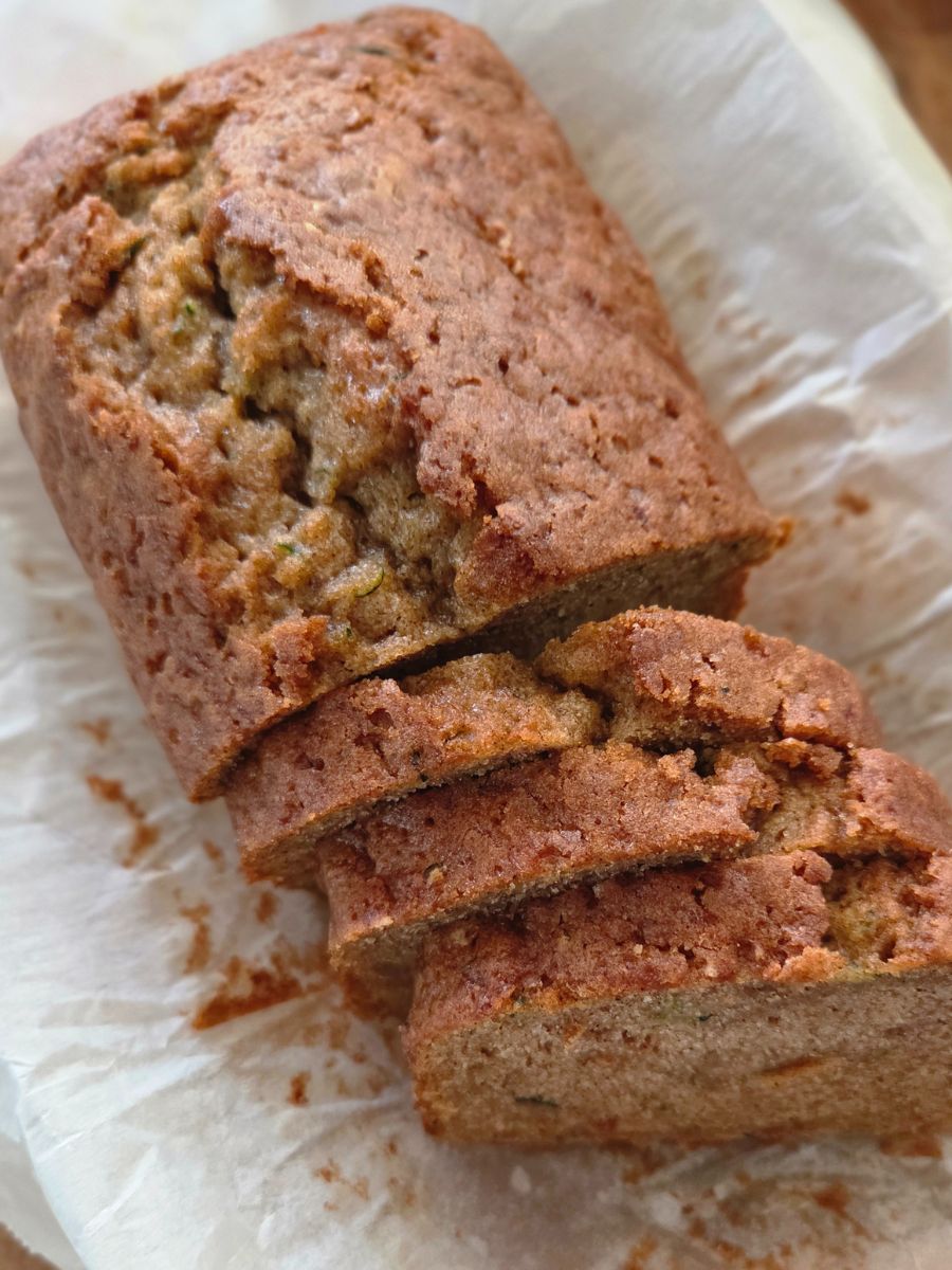 Homemade cinnamon zucchini bread sliced on parchment paper, golden brown crust with soft interior.